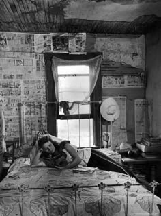 a woman laying on top of a bed in a bedroom next to a large window