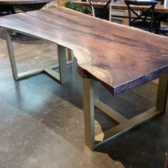 a wooden table sitting on top of a floor next to two tables with chairs in the background