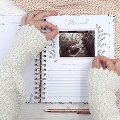 two hands are holding an open book with photos on it