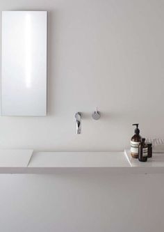 a bathroom sink with soap and lotion on it next to a mirror above the sink