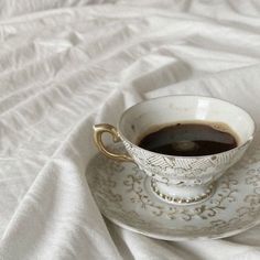 a cup of coffee sitting on top of a saucer next to a white sheet