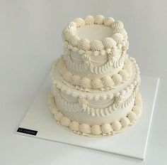 a three tiered white wedding cake sitting on top of a table