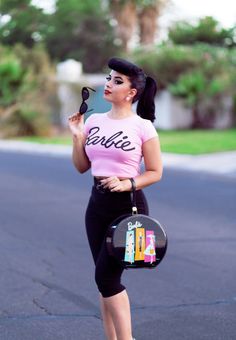 a woman in pink shirt and black leggings standing on street with handbag