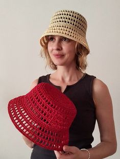 a woman wearing a crocheted hat and holding a red heart shaped object in her hands