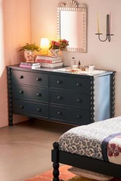 a bedroom with a bed, dresser and mirror on the wall next to each other