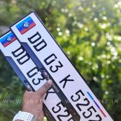 a person holding up two street signs in front of trees