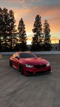 a red car parked in a parking lot at sunset