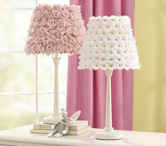 two lamps on a table with pink curtains in the background