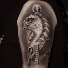 an egyptian tattoo on the back of a man's arm, with an eagle and pyramid