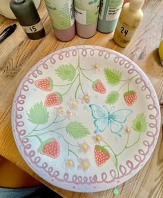 a plate with flowers and butterflies painted on it sitting on a table next to other items