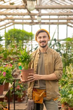 a man holding a potted plant in a greenhouse