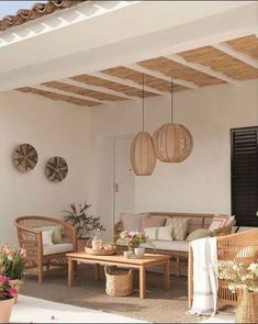 an outdoor living area with wicker furniture and hanging baskets on the ceiling, along with potted plants