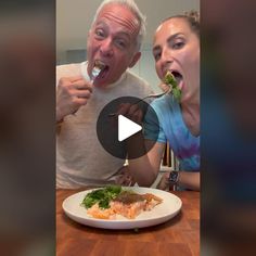 an older man and young woman eating food from a white plate on a wooden table