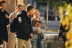 a group of young people walking down the street talking to each other and holding folders in their hands