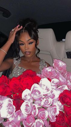 a woman sitting in the back of a car next to red and white roses with her hand on her head