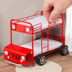 a red toy truck with white bedding and wheels on the floor next to a rug