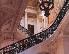 an ornate staircase with wrought iron handrails and chandelier in a building