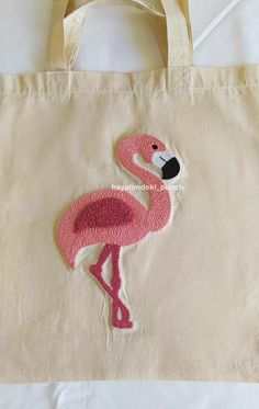 a pink flamingo embroidered onto a tote bag