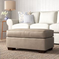 a living room scene with focus on the footstool and the ottoman in the foreground