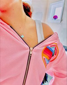 a woman wearing a pink jacket with a rainbow logo on it