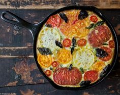 a pizza sitting on top of a pan covered in cheese and toppings with tomatoes