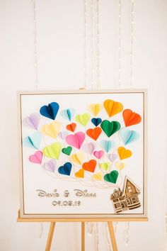 a card with hearts on it sitting on top of a easel next to a string of lights