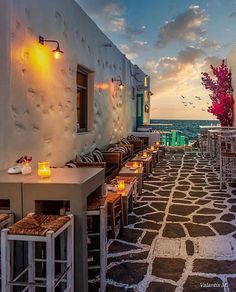 an outdoor dining area overlooking the ocean with candles lit on tables and chairs in front of it