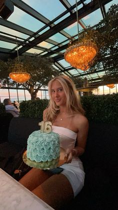 a woman sitting at a table with a cake in her hand