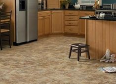 a modern kitchen with wood cabinets and tile flooring, including a stainless steel refrigerator