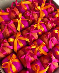 many pink and orange wrapped presents in a box