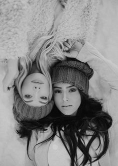 black and white photograph of two women with hats on their heads, one woman has her head wrapped around the other's shoulders