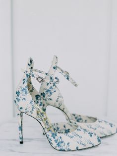 a pair of blue and white high heeled shoes with floral print on the heels