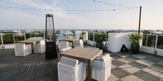 an outdoor dining area overlooking the ocean with white chairs and wooden tables set up for two