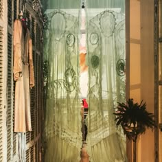 an open window with sheer curtains in front of it and a potted plant next to it