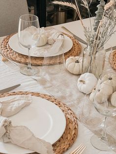 the table is set with white pumpkins and silverware