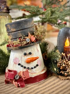 a wooden snowman with a hat and scarf on it's head sitting next to other christmas decorations