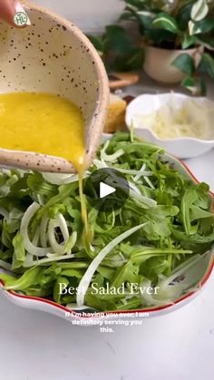 someone is pouring dressing into a salad in a bowl