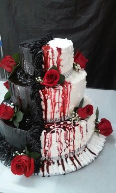 a three tiered cake with red roses on the side and white icing dripping down