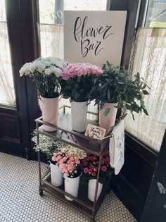 flowers are arranged on a shelf in front of a sign