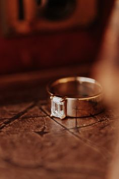 a close up of a wedding ring with a diamond on the side and a person's reflection in the background