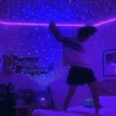 a man standing on top of a bed in a room filled with purple lights and stars