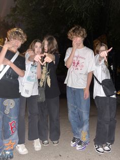 four young boys are standing together and pointing at something in the air with their fingers