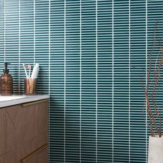 a bathroom with blue tiles on the wall and wooden cabinets in front of it, along with a white sink