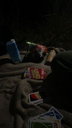 some snacks and drinks are laying out on the beach sand at night, with one bottle in the foreground