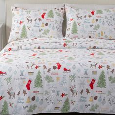 a bed with christmas themed sheets and pillows