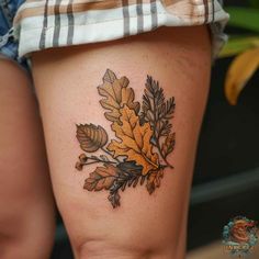 a woman's thigh with an oak leaf tattoo on it