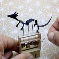 two hands are working on some type of mechanical device that looks like a bird and dragon