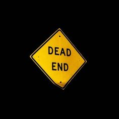 a yellow dead end sign in the dark