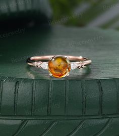 a ring with an orange and white stone in it on top of a green surface