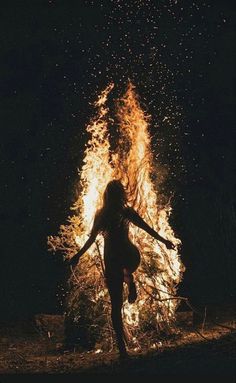 a woman standing in front of a fire